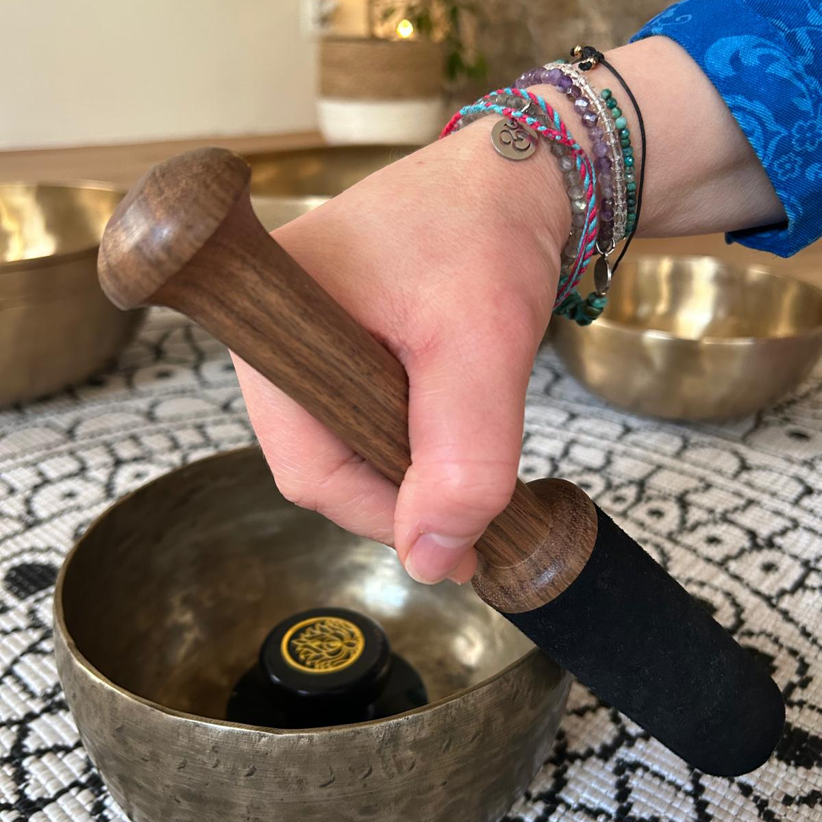Ruka držící paličku vedle tibetské mísy